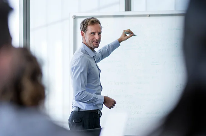 A facilitator writes on a whiteboard during a group working session.