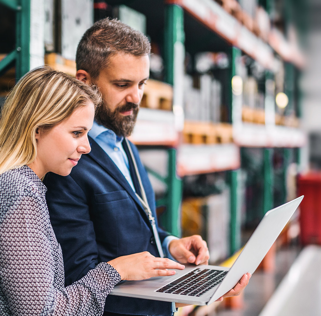 Manufacturers looking at a laptop in a warehouse 